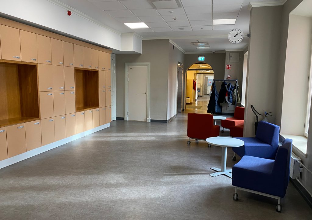 En tom korridor i skolan med stolar och några bord