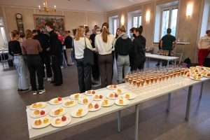 ett dukat bord med bubbel och snittar, studerande i bakgrunden