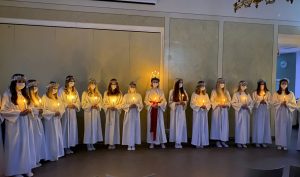 Lucia i mitten med ljuskrona och tärnorna runt omkring