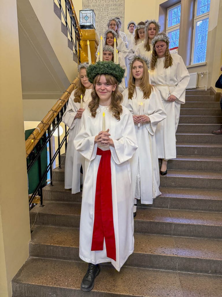 Lucia med följe kommer ner för trappan i skolan