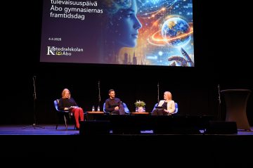 Tre talare sitter på scenen